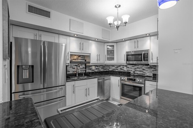 30 Turner St Unit 202, Clearwater, FL 33756 - kitchen featuring appliances with stainless steel finishes, a sink, white cabinets, tasteful backsplash, and a chandelier