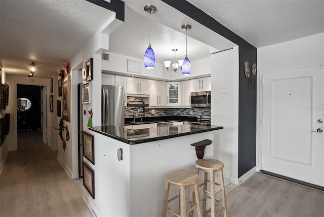 30 Turner St Unit 202, Clearwater, FL 33756 - kitchen with stainless steel microwave, a textured ceiling, light wood finished floors, a breakfast bar, and glass insert cabinets