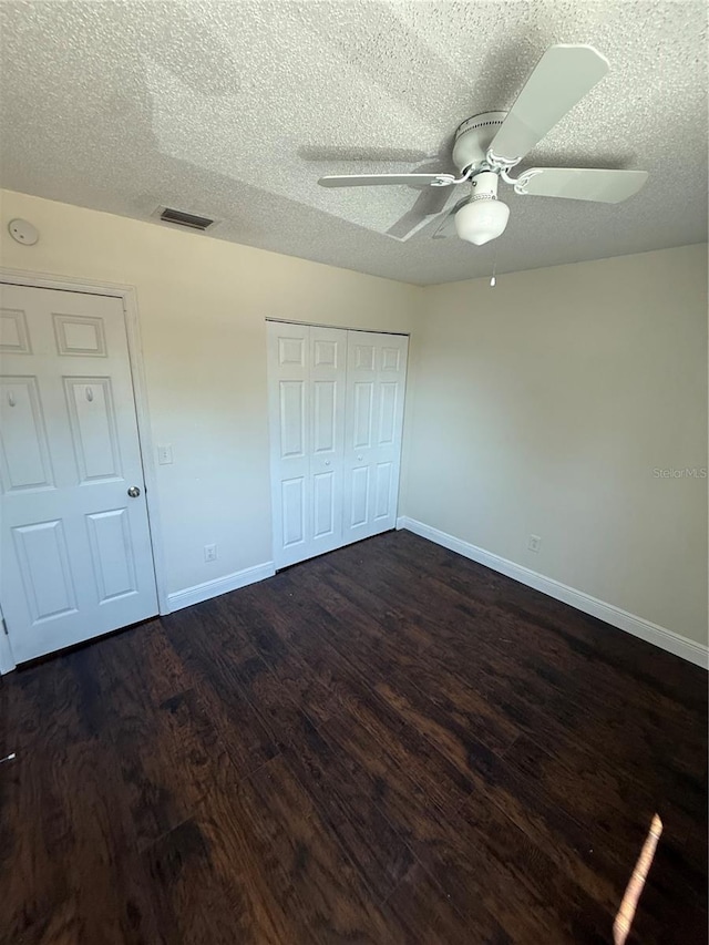 unfurnished bedroom with baseboards, dark wood finished floors, and a textured ceiling