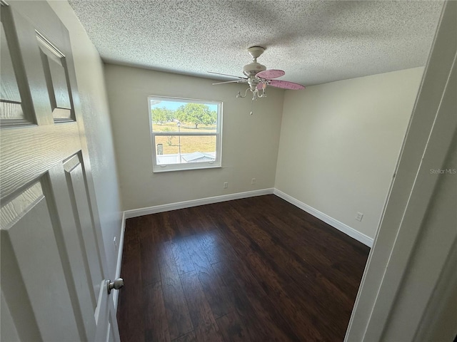 empty room featuring baseboards, a ceiling fan, dark wood-style floors, and a textured ceiling