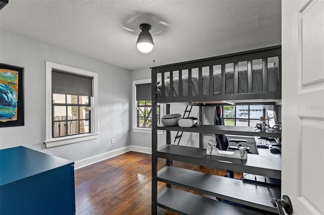 bedroom featuring a textured ceiling, baseboards, a textured wall, and wood finished floors