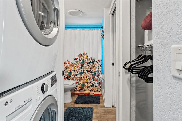 washroom with laundry area, stacked washer / drying machine, and wood finished floors