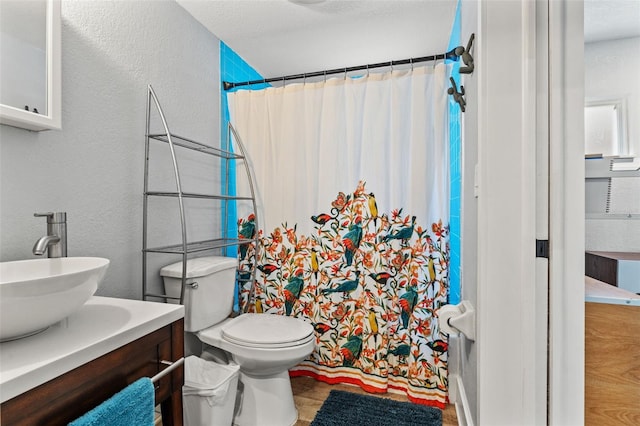 bathroom featuring vanity, a textured wall, a shower with shower curtain, and toilet