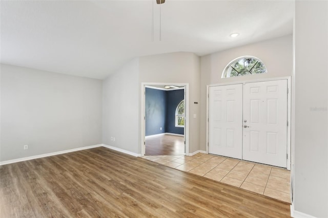 foyer featuring baseboards, wood finished floors, and lofted ceiling