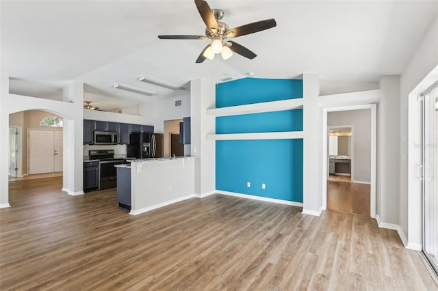 unfurnished living room with wood finished floors, lofted ceiling, baseboards, ceiling fan, and arched walkways