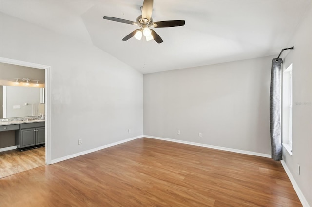 unfurnished bedroom featuring a ceiling fan, baseboards, light wood finished floors, connected bathroom, and lofted ceiling