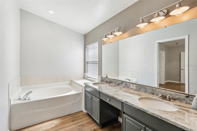 bathroom featuring a sink, wood finished floors, a bath, and lofted ceiling