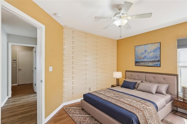 bedroom featuring baseboards, a ceiling fan, and wood finished floors