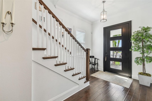 foyer featuring crown molding, baseboards, stairway, and dark wood-type flooring