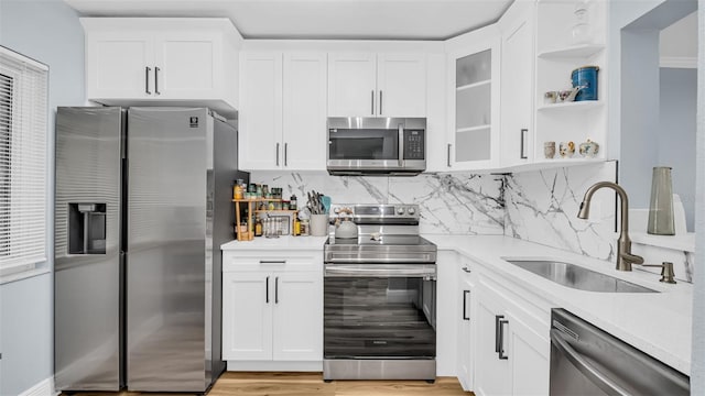 kitchen featuring open shelves, a sink, light countertops, stainless steel appliances, and white cabinetry