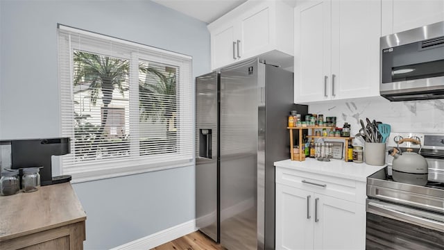 kitchen with light countertops, stainless steel appliances, decorative backsplash, and white cabinetry
