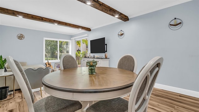 dining area with baseboards, beamed ceiling, and light wood-style flooring