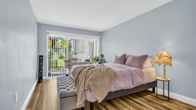 bedroom with baseboards, wood finished floors, and access to outside