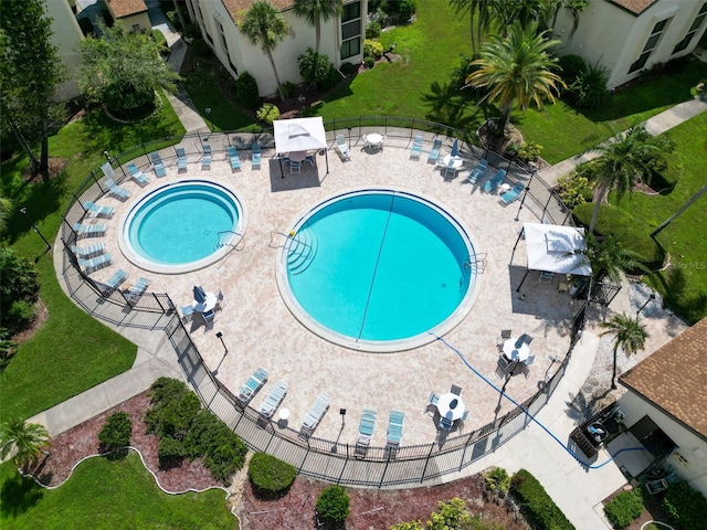 community pool featuring a lawn, a patio area, and fence