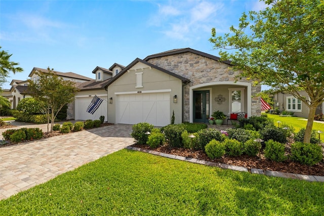 view of front of property featuring a front lawn, stone siding, decorative driveway, stucco siding, and an attached garage