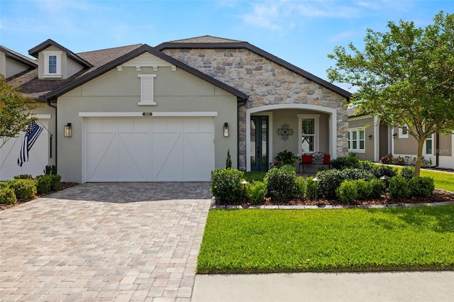 view of front facade featuring decorative driveway, a garage, a front yard, and stucco siding