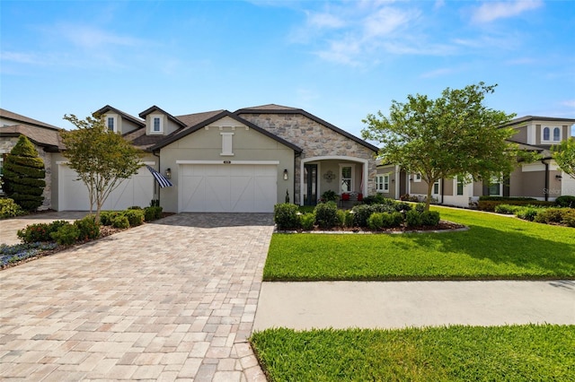 traditional-style home with a front lawn, stone siding, a garage, stucco siding, and decorative driveway