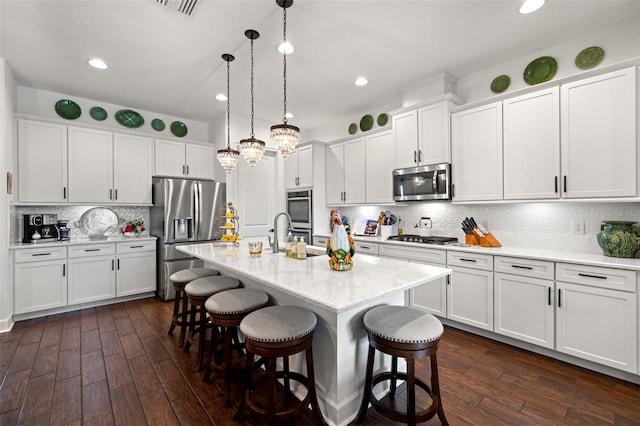 kitchen featuring stainless steel appliances, dark wood finished floors, a breakfast bar, and a sink
