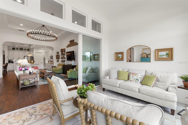 living area featuring a high ceiling, an inviting chandelier, arched walkways, recessed lighting, and dark wood-type flooring