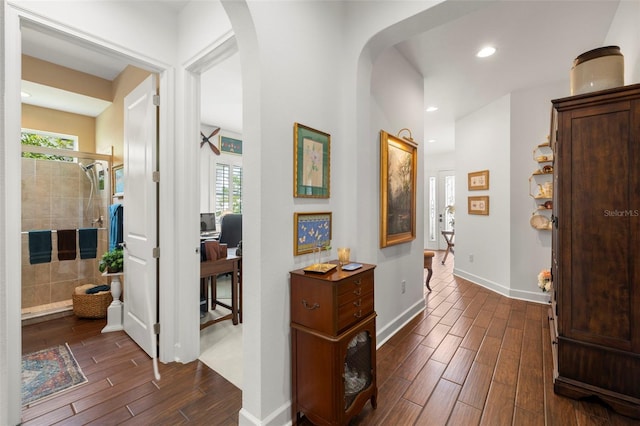 hallway featuring recessed lighting, arched walkways, baseboards, and dark wood-style floors