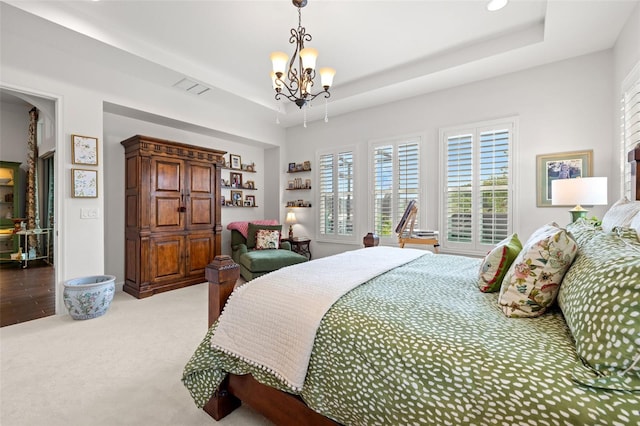 bedroom with a tray ceiling, an inviting chandelier, light carpet, and visible vents