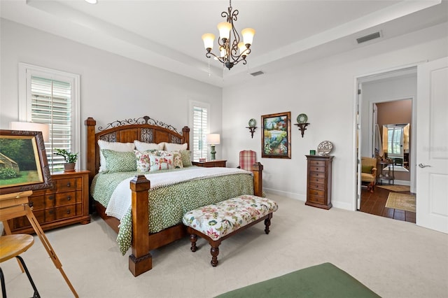 carpeted bedroom featuring an inviting chandelier, baseboards, a tray ceiling, and visible vents