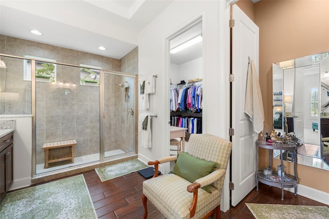 bathroom featuring vanity, baseboards, a shower stall, wood finished floors, and a spacious closet