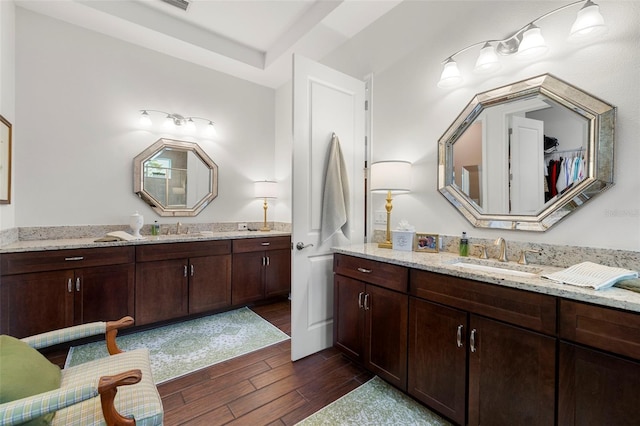 bathroom featuring two vanities, a sink, and wood finished floors
