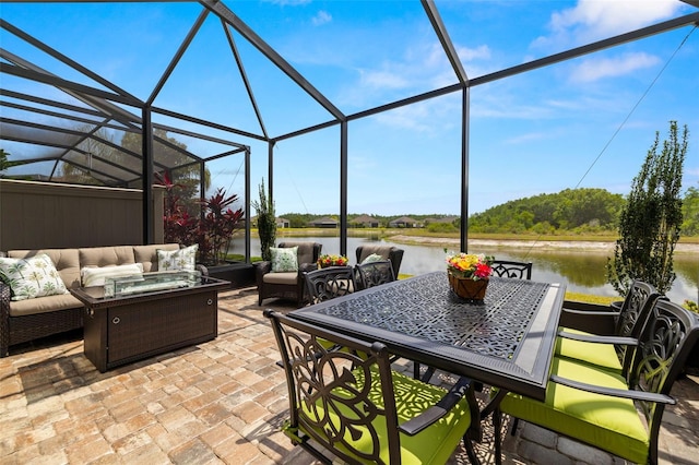 view of patio / terrace featuring glass enclosure, a water view, and outdoor lounge area