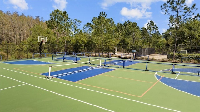 view of sport court featuring fence, community basketball court, a tennis court, and a view of trees