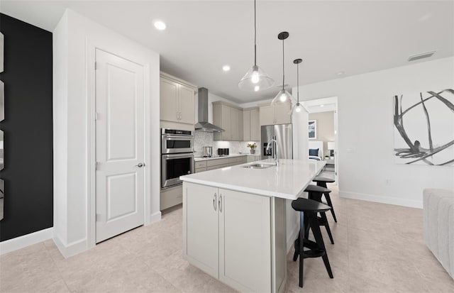 kitchen with wall chimney range hood, a breakfast bar, light countertops, decorative backsplash, and visible vents