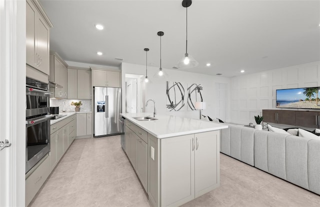 kitchen with a sink, light countertops, stainless steel appliances, open floor plan, and gray cabinetry