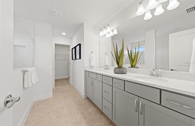 bathroom with a sink, a walk in closet, double vanity, and visible vents