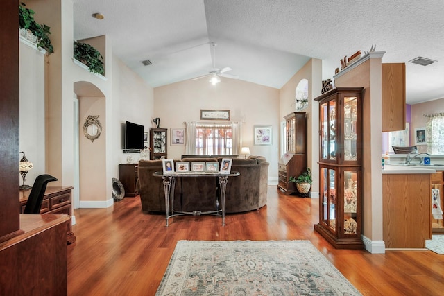living room featuring visible vents, a ceiling fan, wood finished floors, and a healthy amount of sunlight