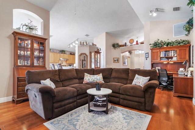 living room with a textured ceiling, a ceiling fan, wood finished floors, and visible vents