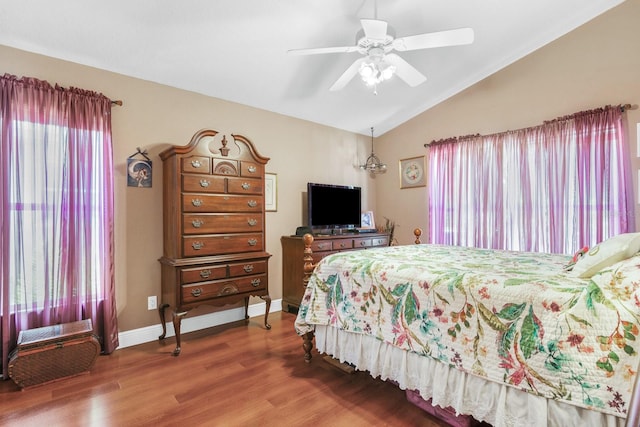 bedroom with a ceiling fan, vaulted ceiling, multiple windows, and wood finished floors