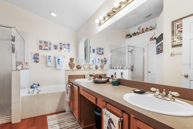bathroom with a garden tub, a sink, a stall shower, and wood finished floors