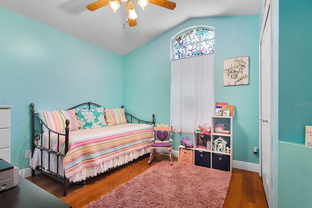 bedroom featuring a ceiling fan, baseboards, vaulted ceiling, and wood finished floors