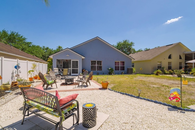 back of house with a fire pit, fence, central AC unit, a patio area, and a lawn
