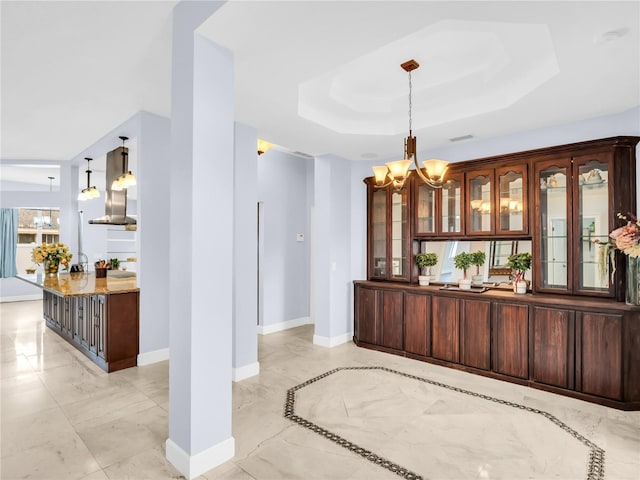 1424 Ridge Shore Dr, Tarpon Springs, FL 34689 - bar featuring light marble finish flooring, a chandelier, a raised ceiling, and pendant lighting