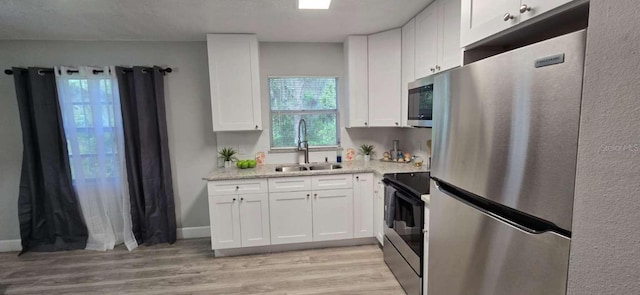 917 Adamson Ct, Lake Alfred, FL 33850 - kitchen with appliances with stainless steel finishes, white cabinetry, light wood-type flooring, and light stone countertops