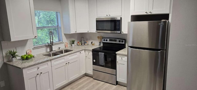 917 Adamson Ct, Lake Alfred, FL 33850 - kitchen with stainless steel appliances, white cabinetry, light wood-type flooring, and light stone counters