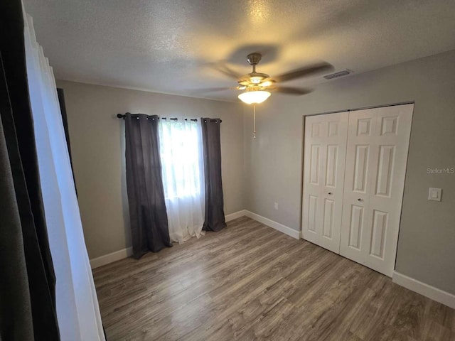 917 Adamson Ct, Lake Alfred, FL 33850 - unfurnished bedroom with a textured ceiling, wood finished floors, ceiling fan, and a closet