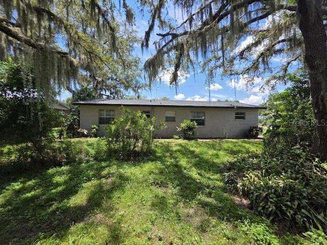 917 Adamson Ct, Lake Alfred, FL 33850 - back of house featuring stucco siding and a lawn