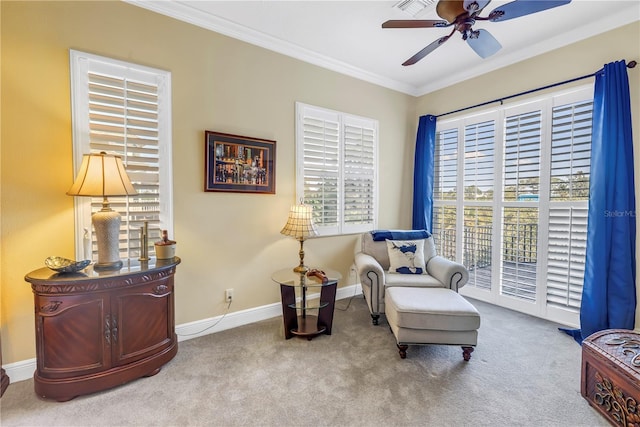 living area with crown molding, a ceiling fan, a wealth of natural light, and carpet