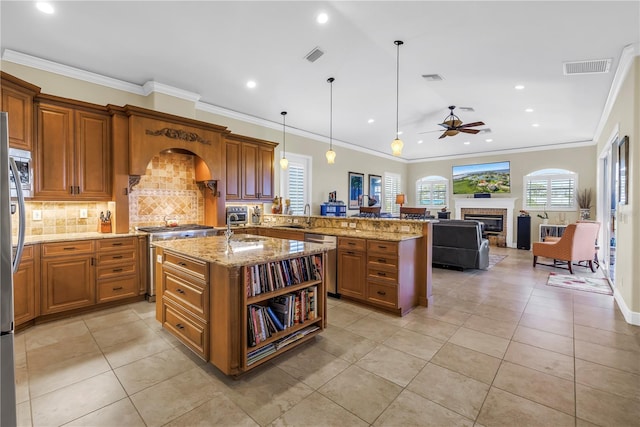 kitchen with ceiling fan, appliances with stainless steel finishes, brown cabinetry, backsplash, and visible vents