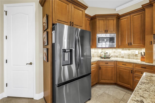 kitchen featuring decorative backsplash, appliances with stainless steel finishes, brown cabinets, and light stone countertops