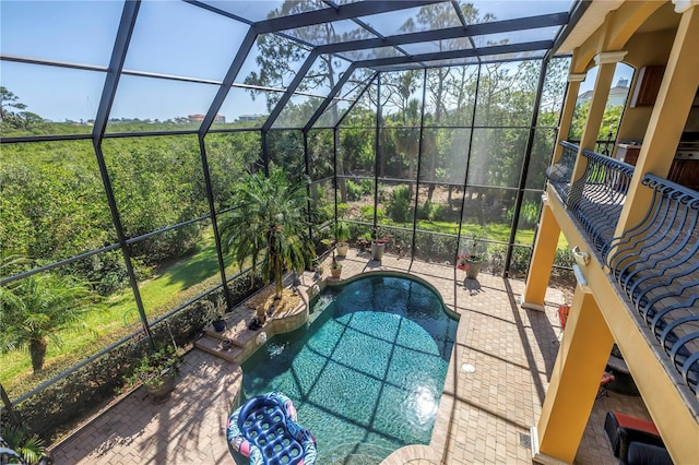 pool featuring glass enclosure and a patio area