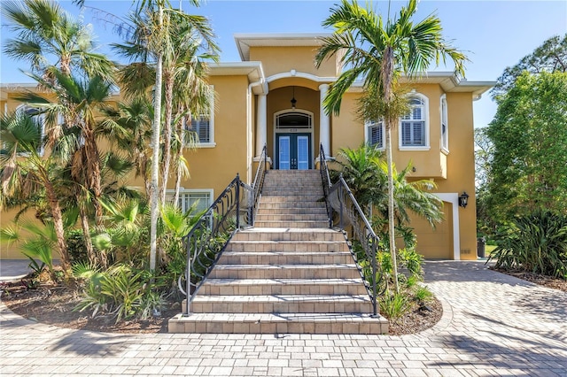 view of front of property with stairway, a garage, french doors, and stucco siding