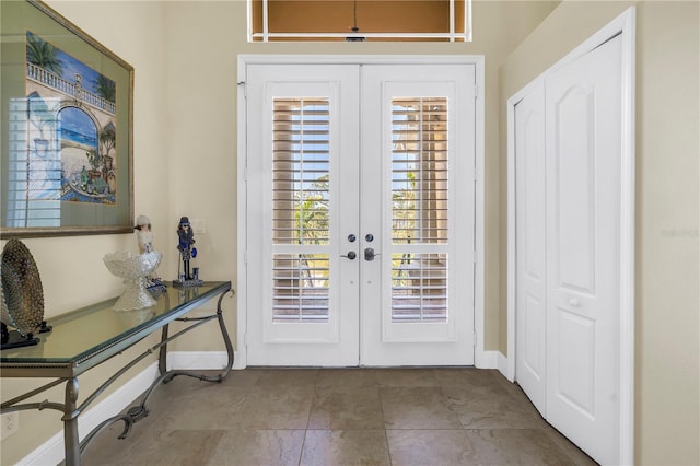 foyer featuring baseboards, french doors, and tile patterned floors
